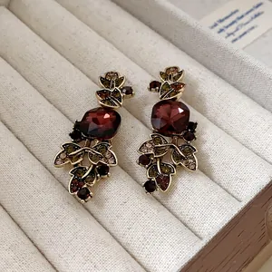 Gros plan de boucles d'oreilles vintage dorées avec cristal rouge et feuilles vertes