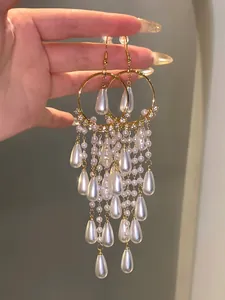 Detailed view of long pearl tassel earrings with gold-tone hoops and teardrop pearls