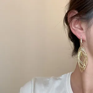 Detailed close-up of gold oval hollow earrings with pleated texture and zircon accents