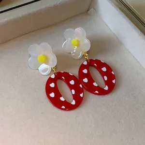 Primer plano detallado de pendientes de resina roja con corazones y flores.
