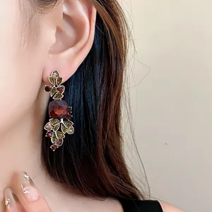 Gros plan de boucles d'oreilles de style palais avec feuilles et cristaux colorés