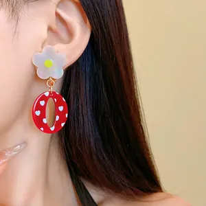 Primer plano detallado de pendientes vintage de resina roja con flores y corazones