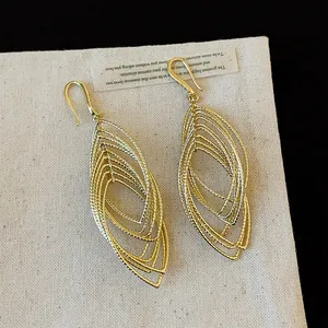 Detailed view of the layered metal texture on golden oval hollow drop earrings