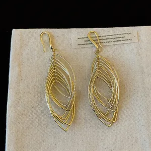 Detailed view of elegant golden multi-layered oval dangle earrings with pleated texture