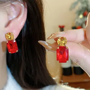 Detailed view of elegant square earrings featuring red and yellow faceted crystals on ear.
