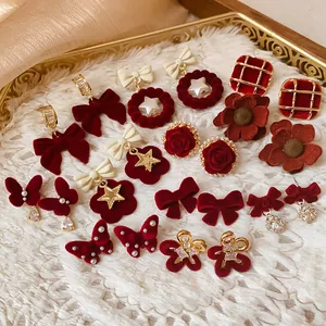 Detailed macro view of various red flocked bow and flower earrings in a gold tray