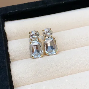 Detailed macro view of square sparkling rhinestone stud earrings in a jewelry box.