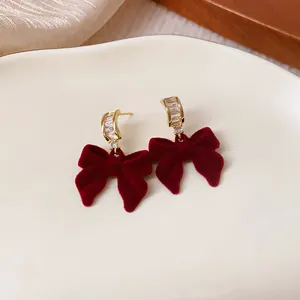 Macro detail of elegant red flocked bow earrings with sparkling rhinestones