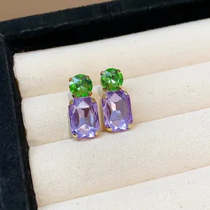 Close-up of rectangular purple and round green crystal stud earrings in jewelry box