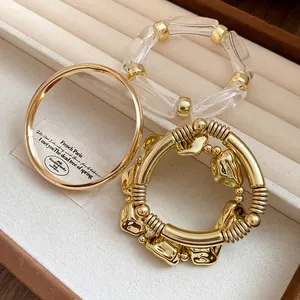 Detailed view of vintage-style gold-tone metal and clear acrylic bracelets in a jewelry tray
