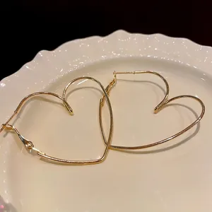 Élégantes créoles dorées évidées en forme de cœur sur une assiette vintage chic