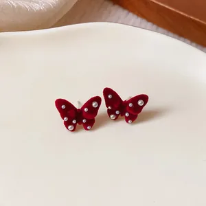 Detail view of red velvet butterfly stud earrings decorated with elegant small pearls