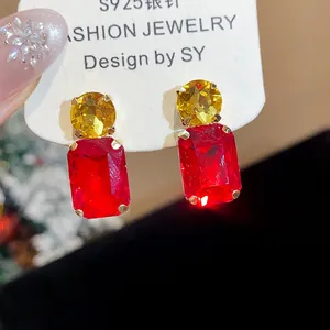 Detailed view of sparkling square red and yellow gemstone stud earrings with silver pins