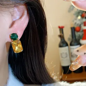 Detail view of elegant geometric stud earrings with green and amber yellow crystals
