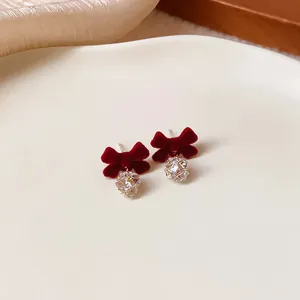 Close-up macro detail of red flocked bow stud earrings with sparkling crystal ball drops