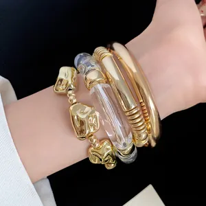 Detail shot of a four-piece set including gold metal and clear acrylic geometric bracelets.
