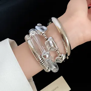 Detail view of a 4-piece set featuring irregular metal and clear acrylic geometric bracelets.