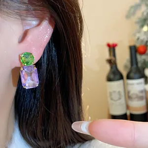 Close-up of elegant green and purple crystal drop stud earrings on an ear