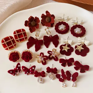 Detailed view of red flocked bow and flower earrings with pearl and crystal accents