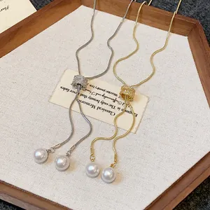 Detailed view of gold and silver snake chain necklaces with zircon sliders and pearls.