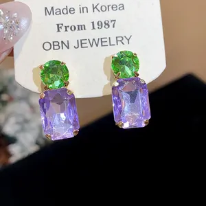 Detailed macro view of green and purple square crystal drop earrings on jewelry card