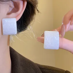 Λεπτομέρεια από λευκά τετράγωνα σκουλαρίκια ρητίνης με λαμπερό μαργαριταρένιο φινίρισμα