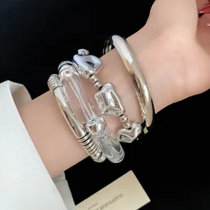 Detail showing four-piece set of silver metal and clear acrylic geometric bracelets