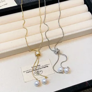 Detail view of gold and silver snake chain necklaces with zircon slider and pearl charms