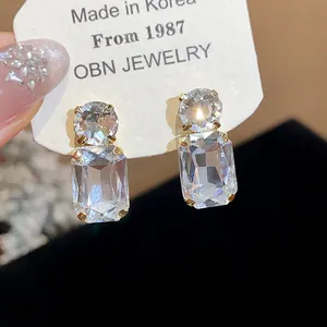 Close-up of elegant square crystal stud earrings with gold-toned prong setting