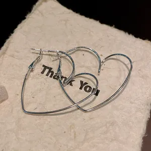 Détail macro montrant le design élégant des boucles d'oreilles créoles cœur argent.