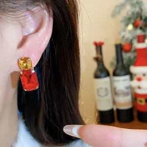 Close-up shot of elegant square red crystal earrings with yellow gemstone detail on ear