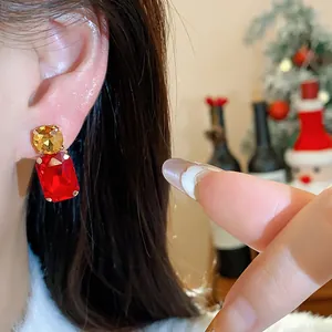 Close-up detail of a square red gemstone earring with golden stud on ear for women