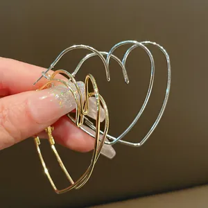 Vue détaillée de grandes boucles d'oreilles créoles évidées en forme de cœur doré
