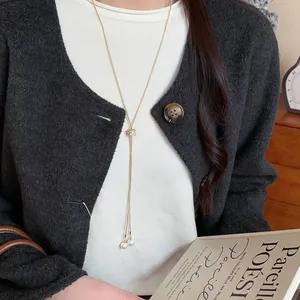 Close-up of an elegant gold Y-shaped necklace featuring white pearls and a zircon knot