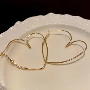 Gros plan de boucles d'oreilles créoles cœur évidé dorées sur une assiette blanche décorative