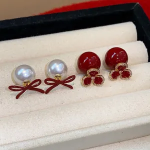 Elegant pearl earrings featuring red bows and jeweled flower designs in a gift box