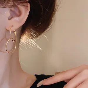 Détail de boucles d'oreilles dorées en forme de cœur creux sur l'oreille