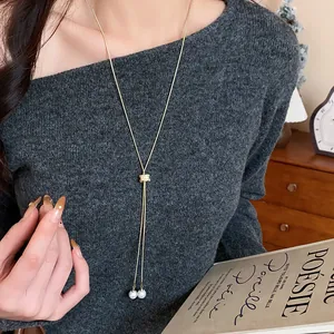 Detail of minimalist long sweater chain with zircon clasp and elegant pearls