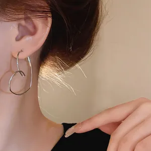 Gros plan d'une boucle d'oreille en forme de cœur argenté portée par un mannequin asiatique.
