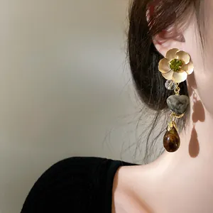 Close-up detail of elegant ethnic style flower and heart dangle earrings worn by a model