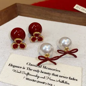 Detail view of vintage red flower and white bow pearl earrings on a wooden tray
