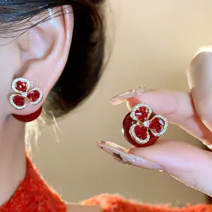 Close-up of elegant flower earrings with red heart-shaped petals and red beads.