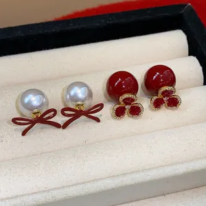 Detail view of vintage red bow pearl earrings and red floral crystal stud jewelry