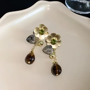 Close-up of elegant flower and heart drop earrings with green crystal accents