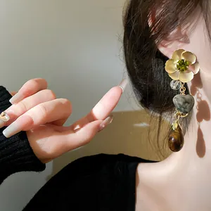 Close-up detail of a vintage flower and heart dangle earring worn on a female ear