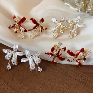 A detailed view showing zircon flower stud earrings in red, white, and pearlescent.