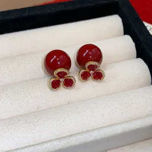 Close-up view of elegant vintage red pearl earrings with pavé crystal flower detail.