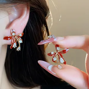 Macro detail of elegant red flower stud earrings with shimmering zircons and 18k gold finish.
