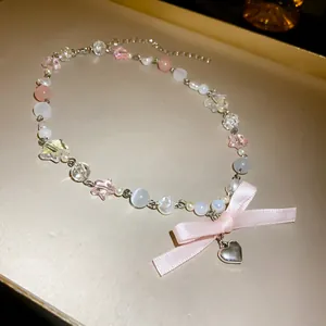 Close-up of a sweet pink bow necklace with cat-eye stones and a silver heart pendant
