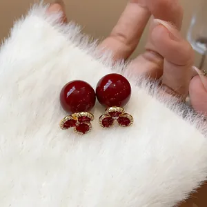 Macro view of vintage gold earrings with deep red pearls and floral crystal accents